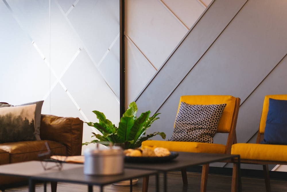 A calm hospital waiting area with upholstered chairs, a low table and a fern